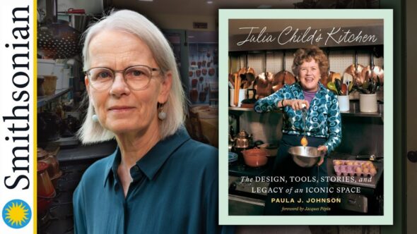 Author Paula J. Johnson with grey hair just above her shoulders, wearing glasses and a blueish green button up blouse. The book cover of Julia Child's Kitchen. Background is an image of a large kitchen full of kitchen implements, utensils, and accessories.