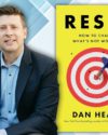 The author in a light blue button up shirt and dark blue blazer. Features the book cover of Reset : How to Change What's Not Working by Dan Heath.